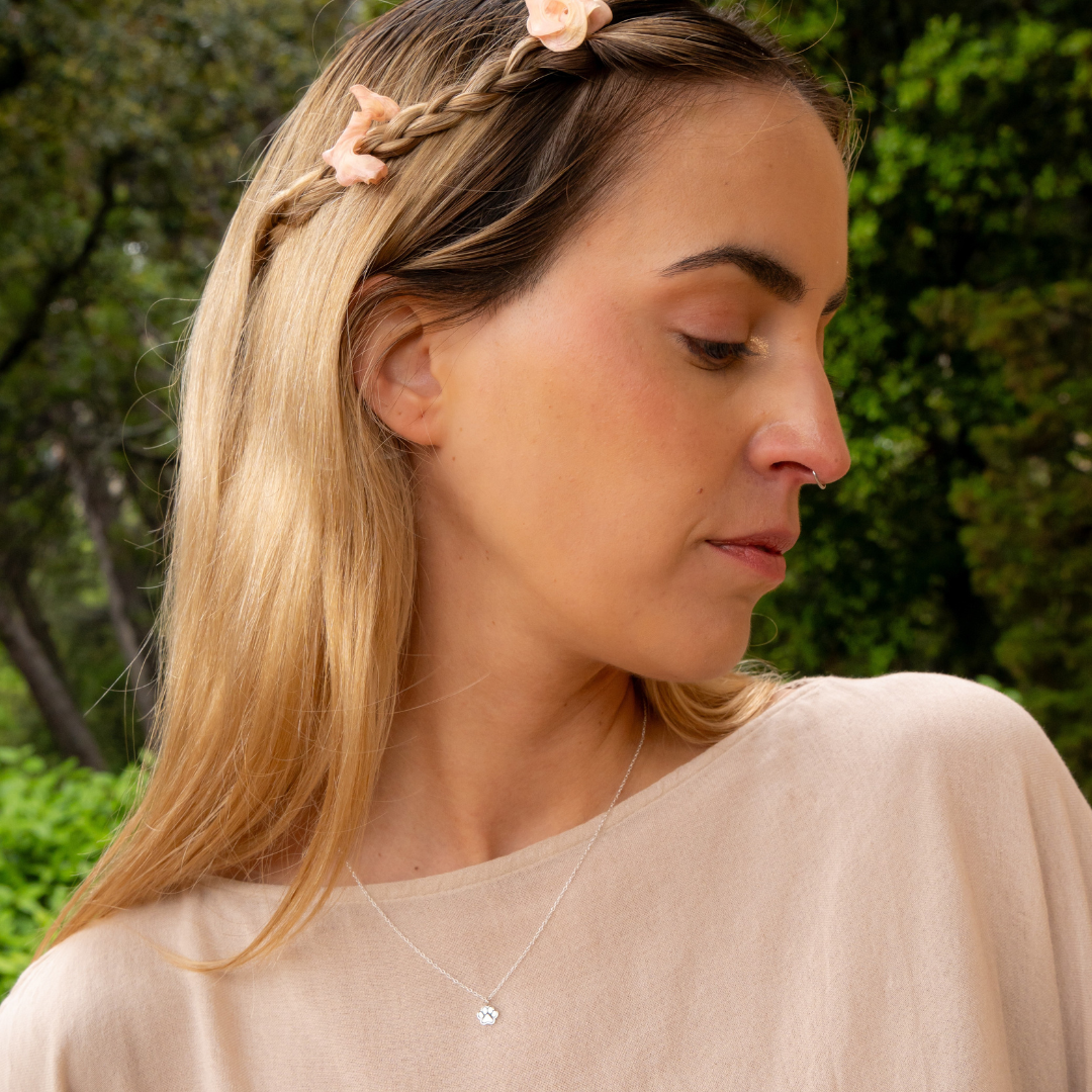 Model wearing sterling silver necklace with small paw print charm, perfect pet keepsake.
